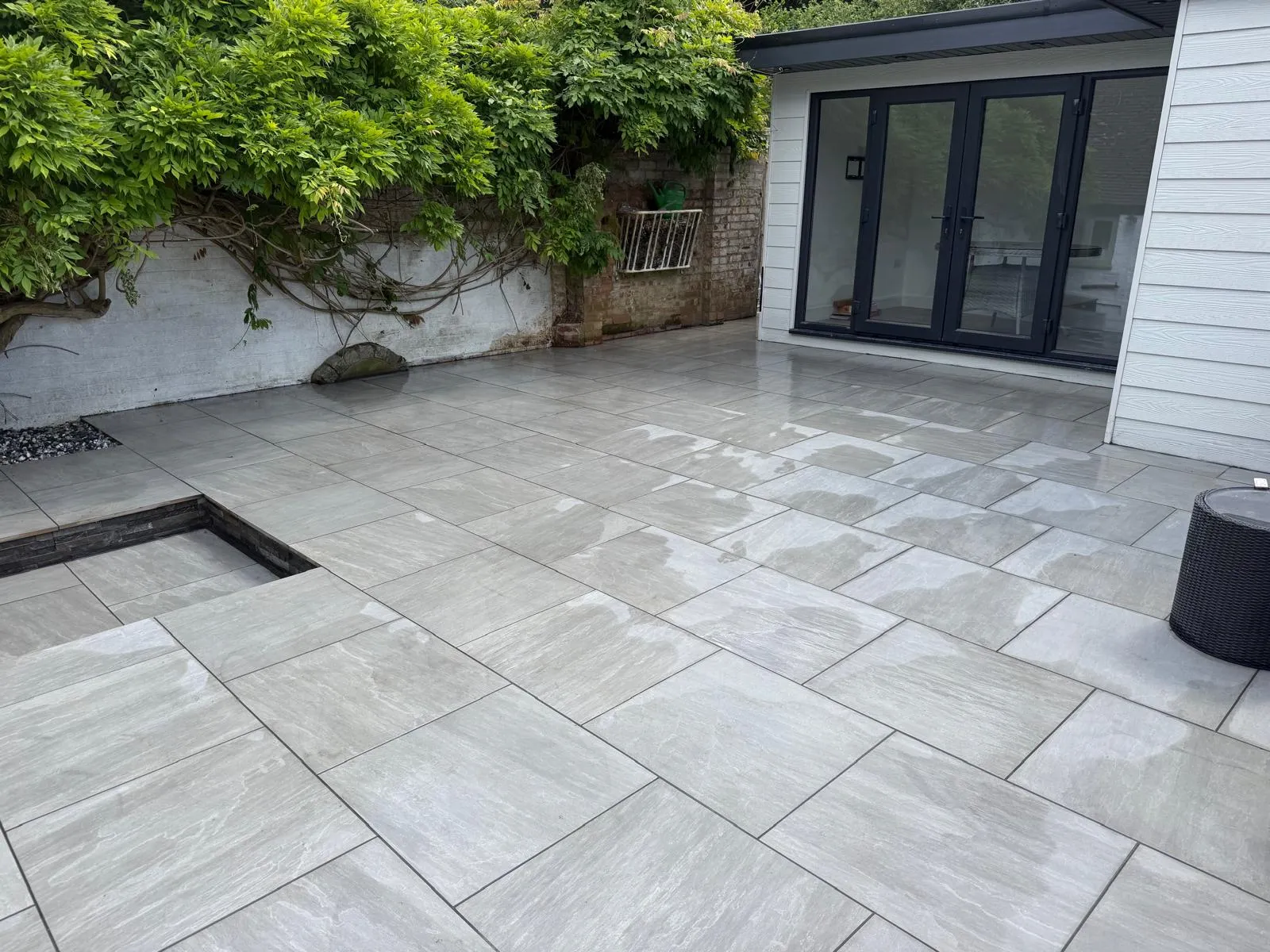 Grey porcelain patio opening onto a rear garden room, built by Prestige Landscapes in Farnborough Village