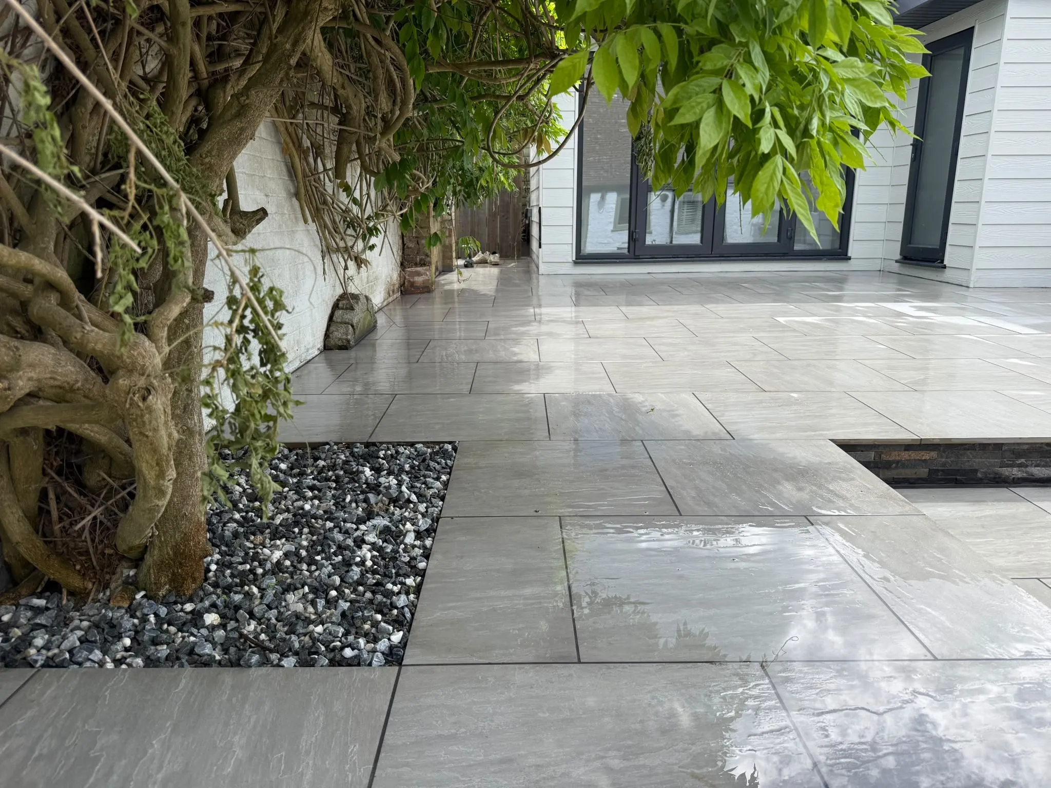 Grey porcelain courtyard paving with wisteria and gravel bed by Prestige Landscapes