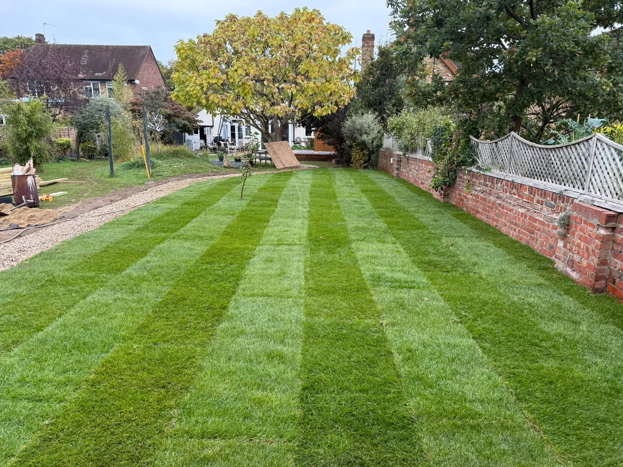 Neatly striped lawn beside a brick wall laid by Prestige Landscapes