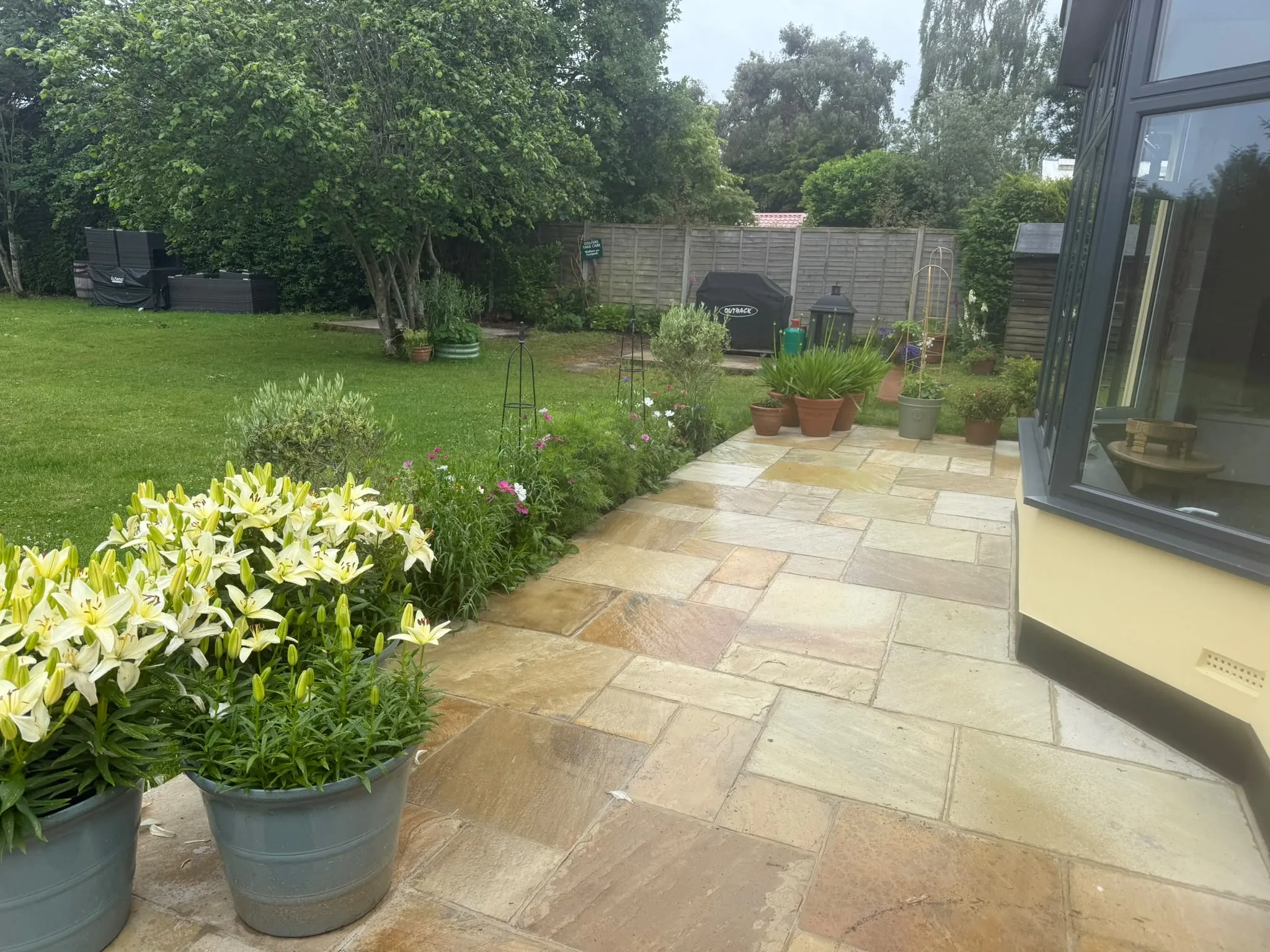 Indian sandstone patio with planted borders by Prestige Landscapes